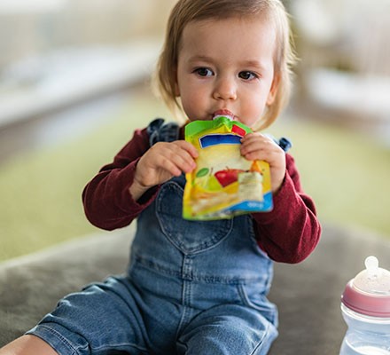 A young toddler sucking a food pouch