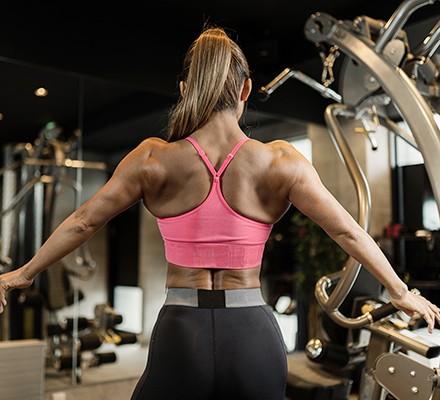A woman flexing her back muscles in a gym