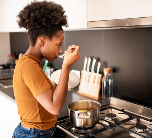 Young woman preparing soup