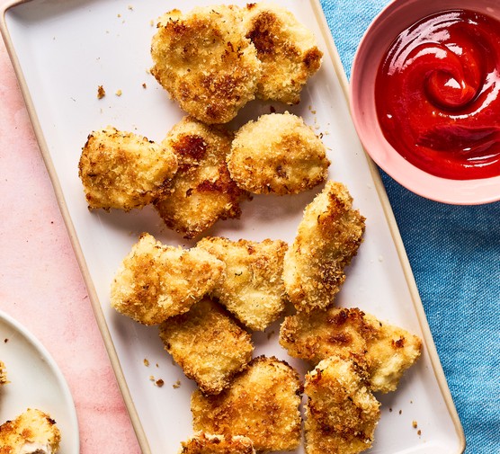 Chicken nuggets on a white plate with a dipping sauce on the side