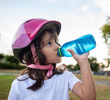 Girl drinking water bottle in park