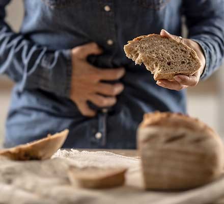 A person holding their stomach with a loaf of bread in the other hand
