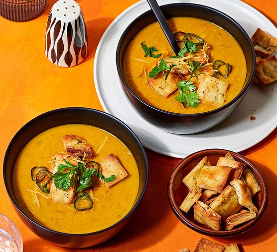 Two bowls of curried coconut lentil soup with naan croutons