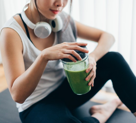 Young woman drinking green smoothie after yoga