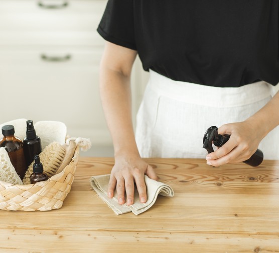 Woman's hand wiping dust using spray and natural fabric cleaning on dirty table. (Getty)