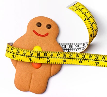 A gingerbread person with a tape measure wrapped around the waist