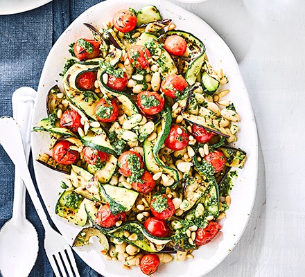 Grilled vegetables with cannellini beans & vegan pesto on a white serving platter with cutlery