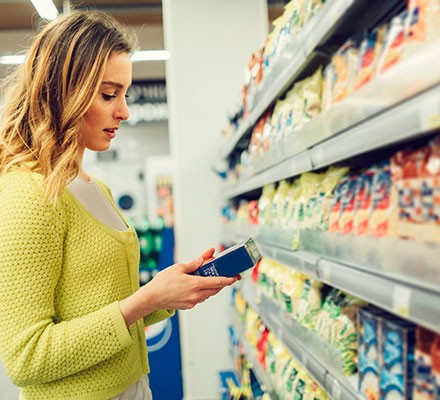 A woman shopping reading a food label
