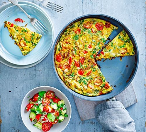 A frittata in a frying pan with avocado salsa in a bowl