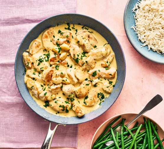 Garlic chicken in a pan with green beans and rice alongside