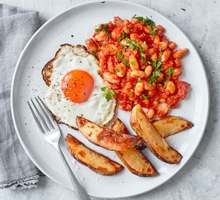 Egg, chips and beans on plate with fork
