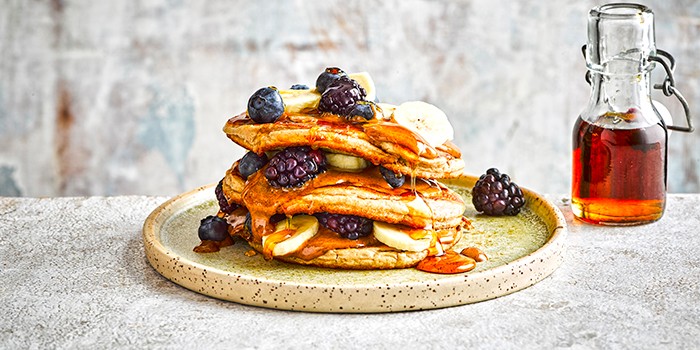 Stack of protein pancakes with nut butter and berries