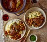 A slow cooker and two bowls of coq au vin, served with mash