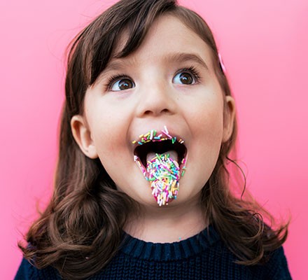 A young girl with sugar sprinkles on her tongue