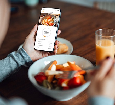 Someone using a mobile app to track their calories while eating a bowl of food