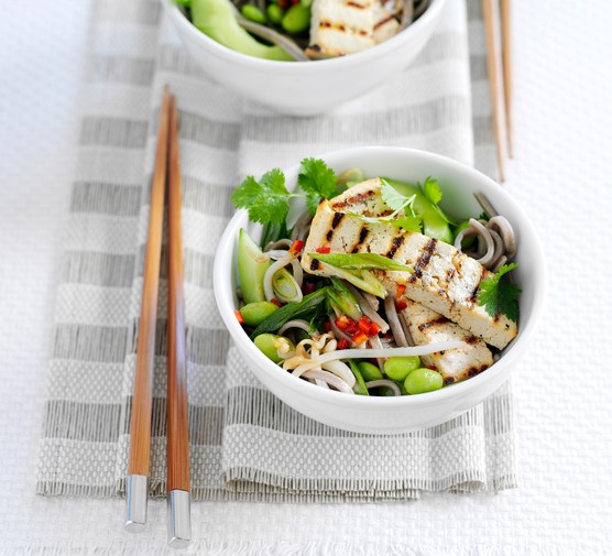 Grilled tofu with noodles and vegetables in a bowl with chopsticks