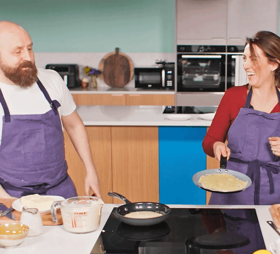 Cassie and Barney flipping pancakes in the Good Food Test Kitchen